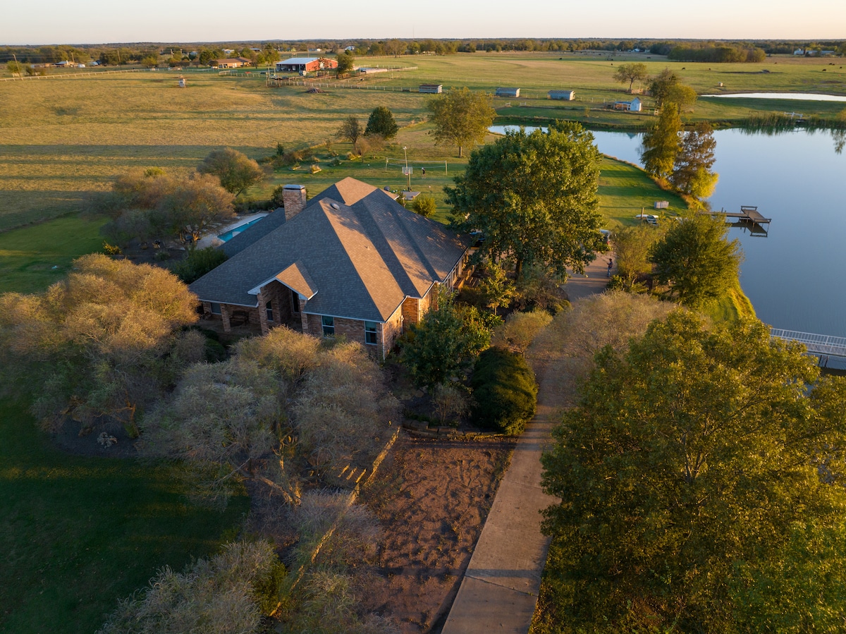 Aerial view of Lavender Hill Farmhouse with pool and fishing pond at golden hour